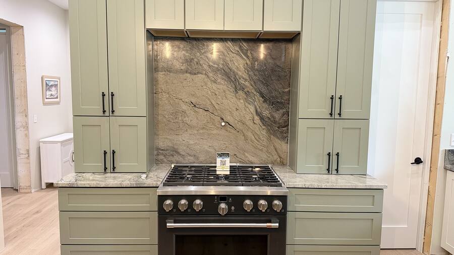 Quartzite slab backsplash, sage-green cabinetry